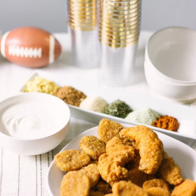 Nuggets and strips in a bowl on a plate with gold settings.