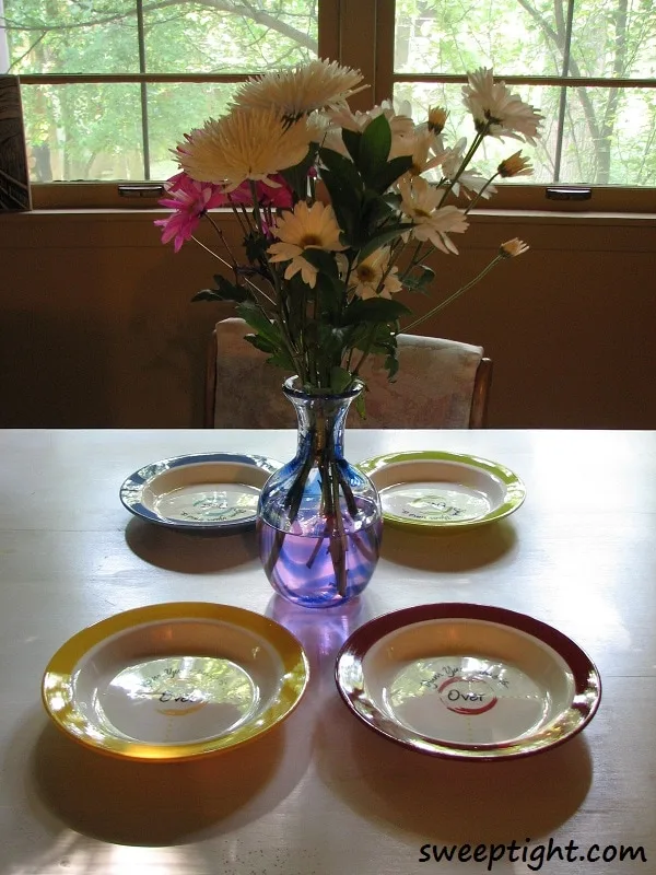 Table set with Yum Yum dishes and flowers in a vase as the centerpiece. 