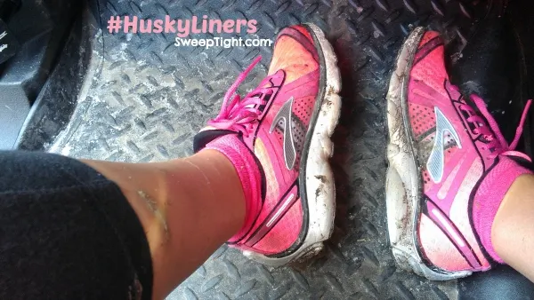 Two pink shoes on a Husky floor liner in a truck. 