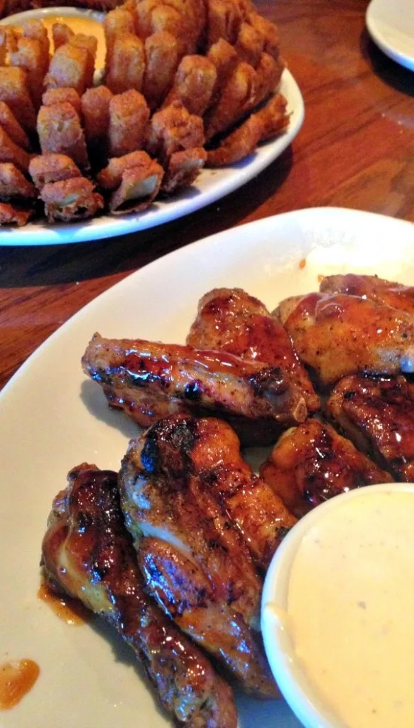 Bloomin' onion and wings on a table. 