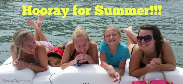 Four girls smiling on the back of a boat. 