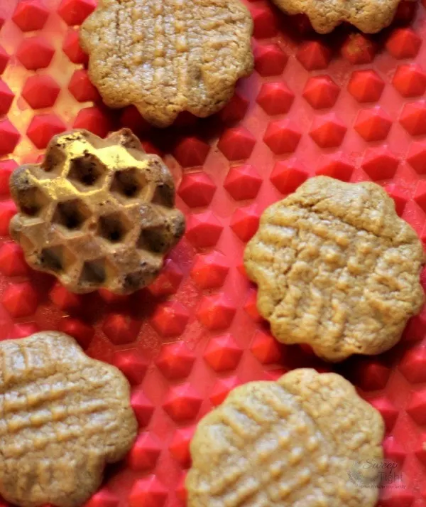 Peanut butter cookies on a red baking mat. 