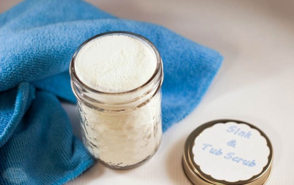 A jar of tub scrub, a blue towel, and the labeled lid. 