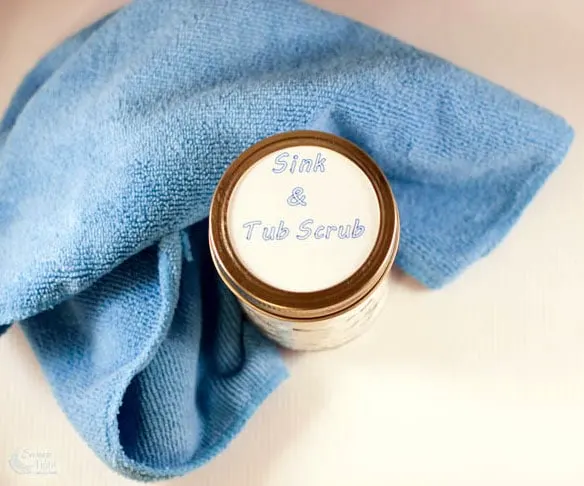 A towel and jar of sink and tub scrub. 