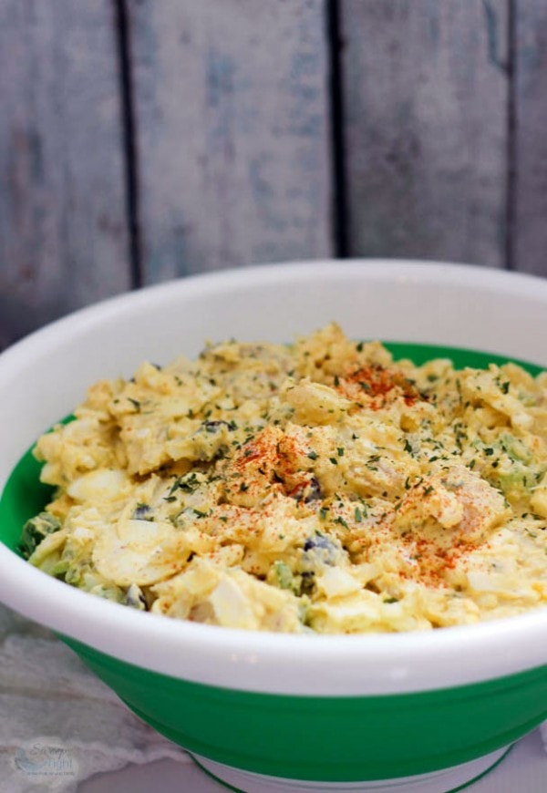 Container filled with egg salad topped with paprika. 