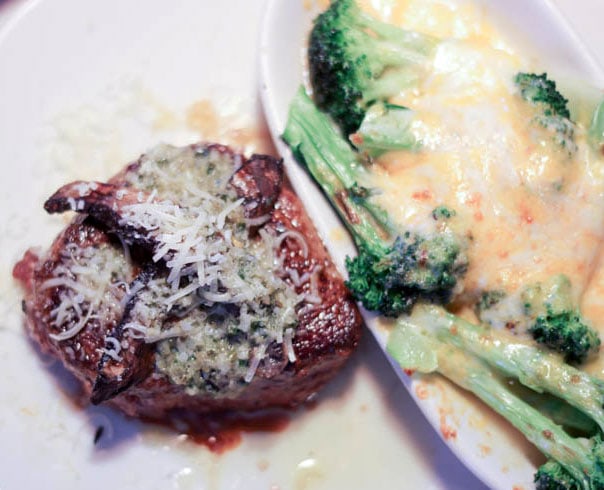 Steak and broccoli with melted cheese on top. 