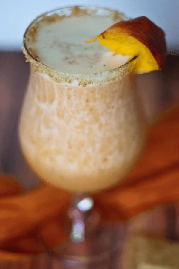 Peach Cobbler Margarita in a glass with a fresh peach garnish