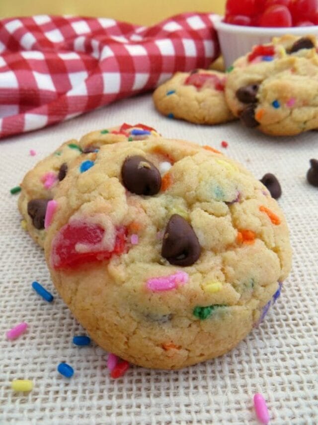 Banana split cookies with chocolate chips and cherries on a table.