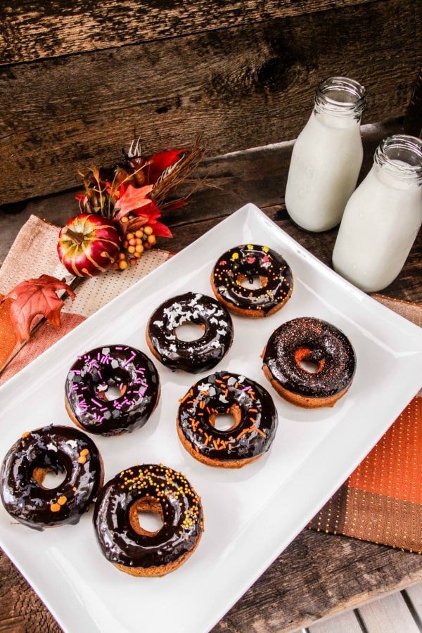 Gingerbread donuts in rows next to milk and fall decor on table.