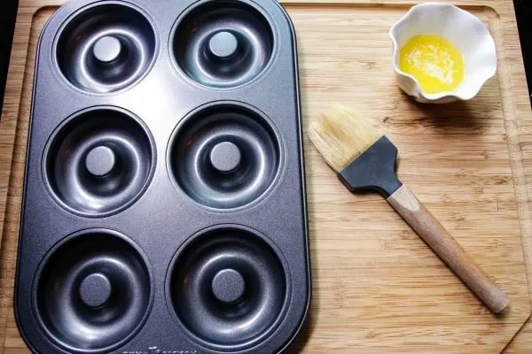 Melted butter, pastry brush, and empty donut pan.