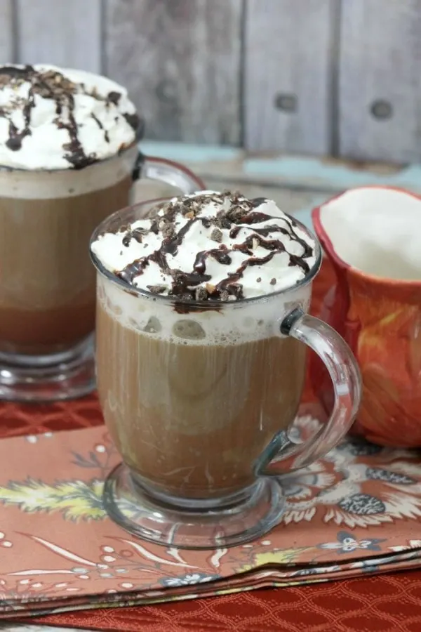 Mocha cookie crumble cappuccinos in clear mugs on a table. 