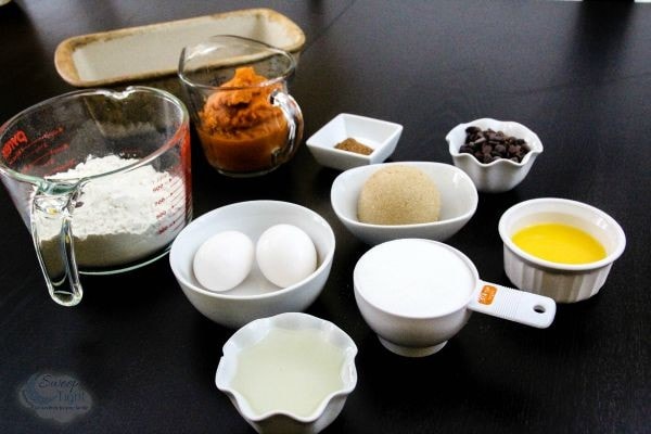 Flour, eggs, pumpkin, butter, and other ingredients in bowls. 