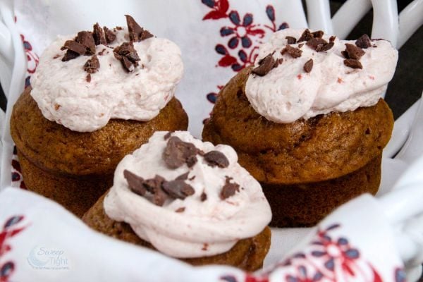 Pumpkin muffins with cranberry frosting topped with chocolate shavings. 