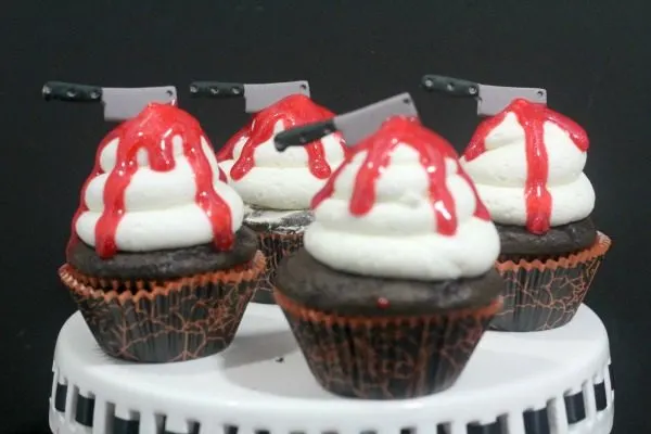 Chocolate cupcakes with knives and red icing dripping down. 