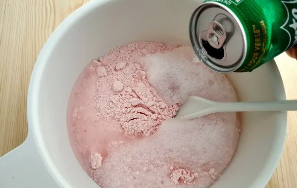 Pouring sprite into strawberry cake mix. 
