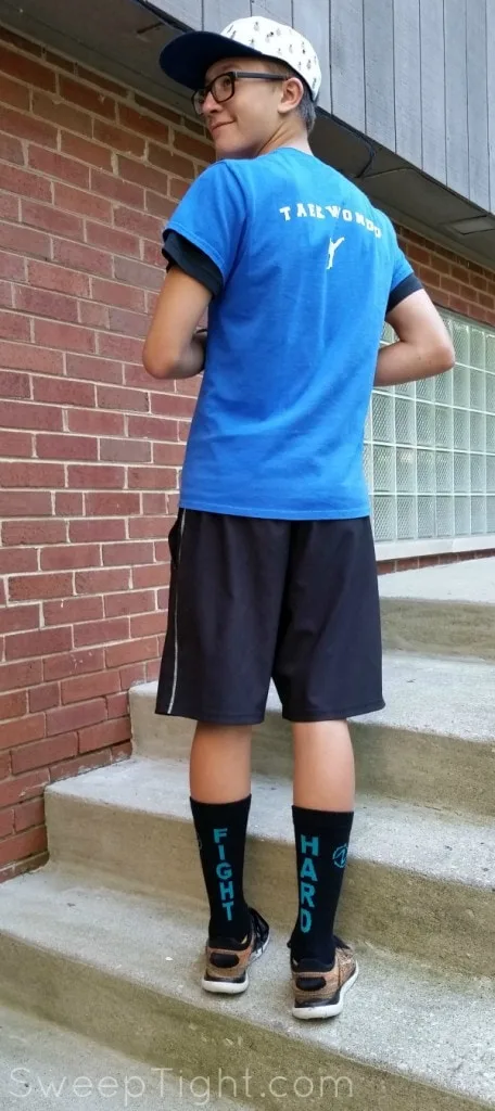 Teenage boy wearing tall colorful socks with inspirational sayings on them.