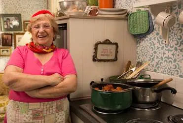 Nonna standing in the kitchen with a pot of sausage. 