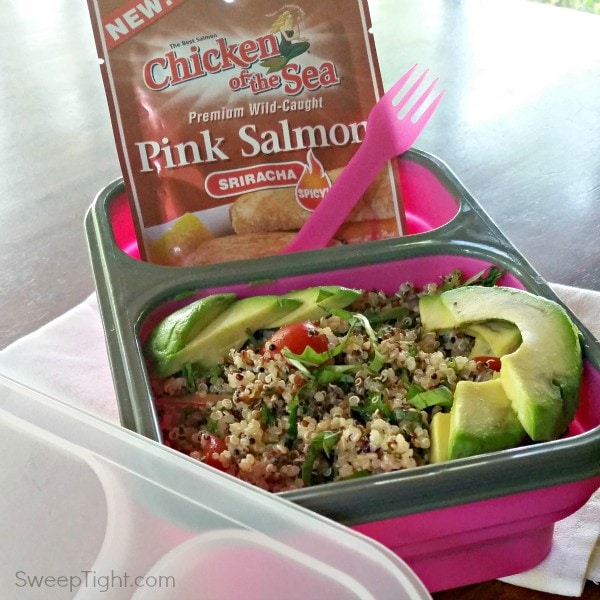Pink bento box with salmon, avocado, quinoa, and veggies. 
