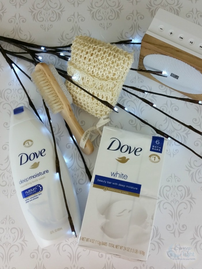 Dove body wash, bar soap, loofah, and a speaker. 
