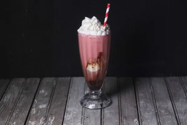 Red shake in a glass with whipped cream and a straw
