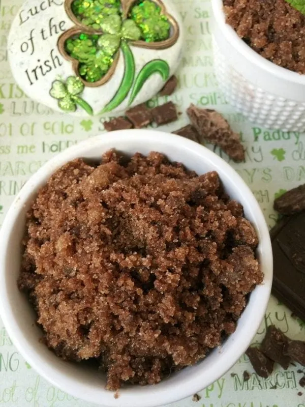 A bowl of sugar scrub next to an Irish pin and chocolate shavings. 