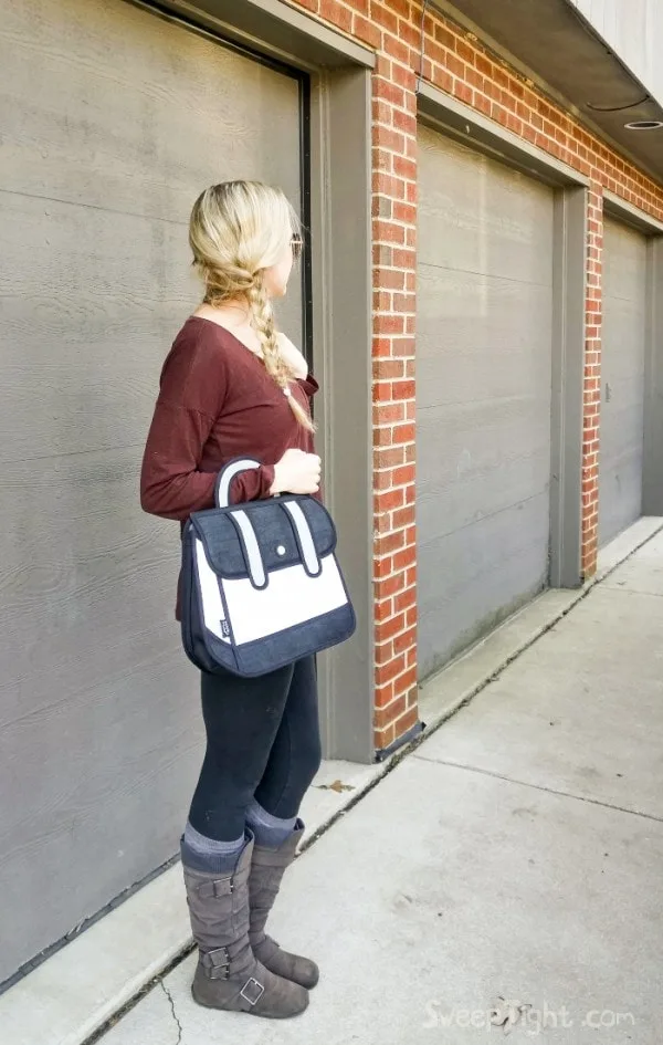 Shelley standing with a comic book drawing purse. 