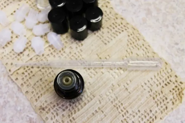 A pipette sitting next to roller bottle jars. 