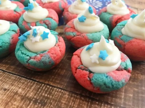 Pink and blue cookies filled with white frosting and star sprinkles.