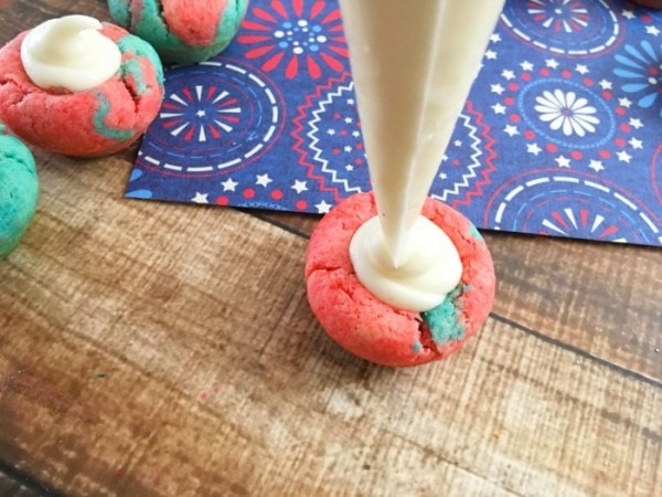 Piping white frosting into red and blue cookie.