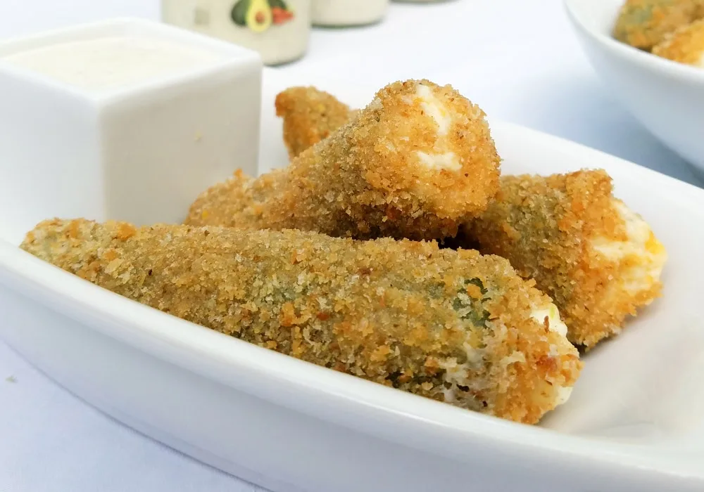 Jalapeño poppers with breading on a tray with dip. 