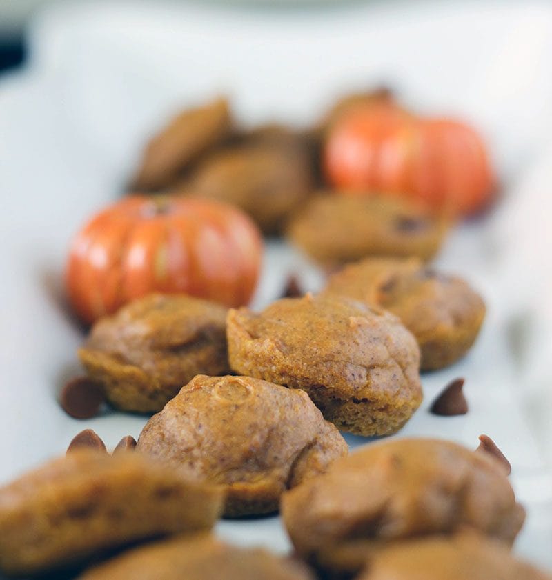 Pumpkin mini cakes on a tray with pumpkin decorations and chips.