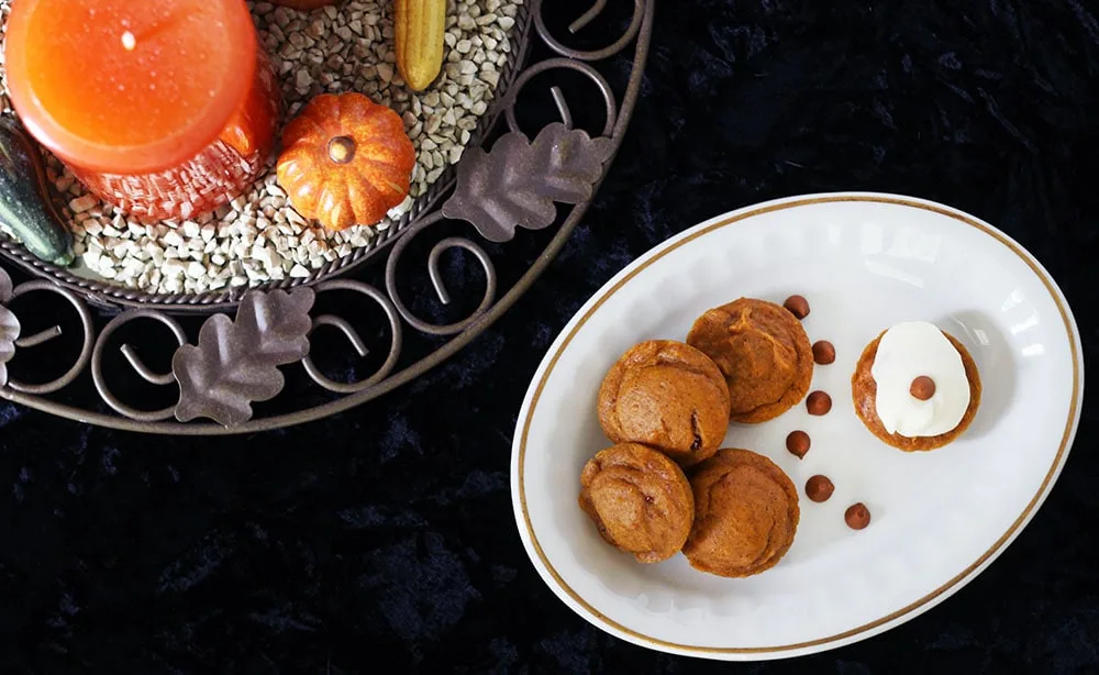 Pumpkin cake bites with chips on a white table with a black background with more Thanksgiving decor next to it. 