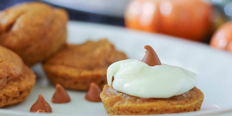 Little pumpkin cakes on a tray with pumpkin decor in the background.