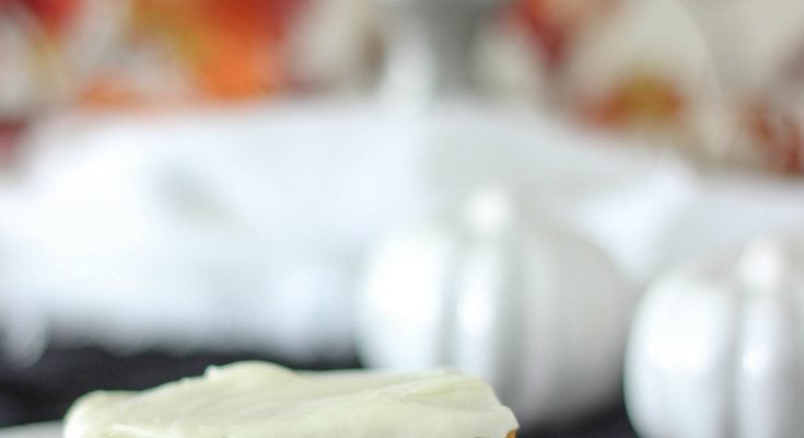 Pumpkin slice topped with cream cheese frosting sitting on a white plate.