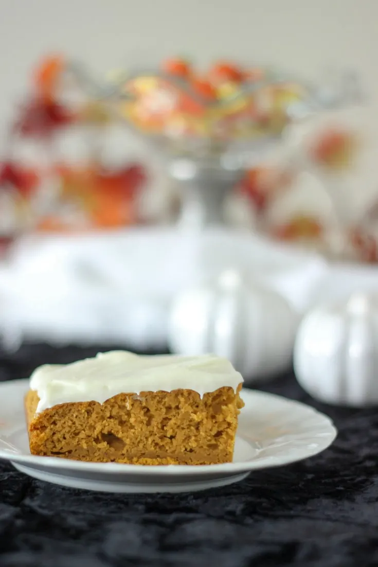 Pumpkin slice topped with cream cheese frosting sitting on a white plate. 