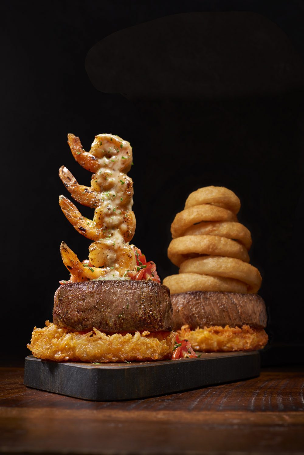 Steak stacked with shrimp and onion rings. 