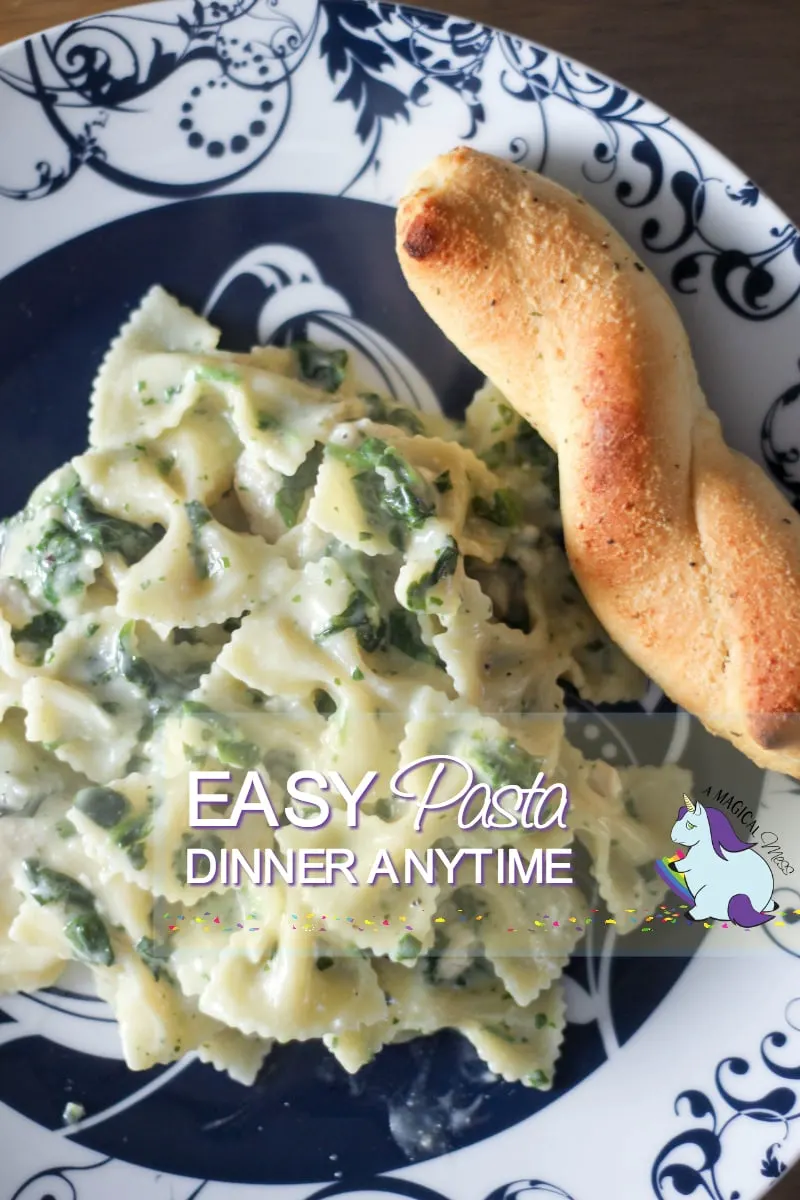 Pasta dinner on a plate with a breadstick.