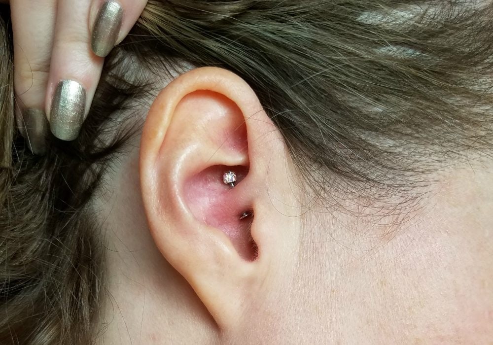 Holding hair back to see the daith piercing in an ear. 