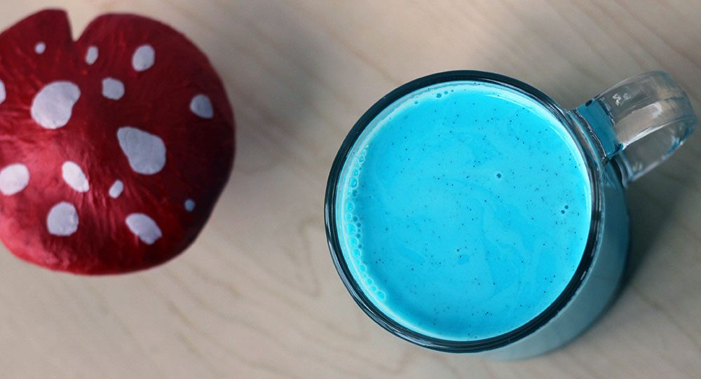 Blue drink in a clear mug next to a vintage Smurf toadstool hut. 