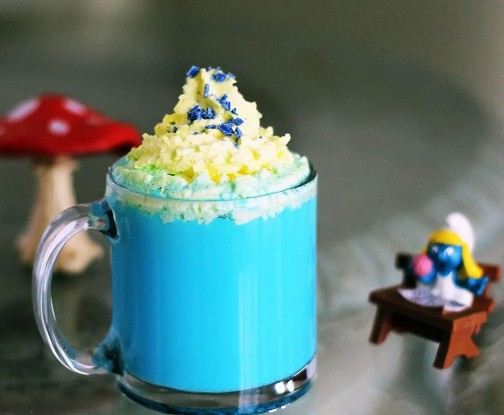 Blue drink with yellow whipped topping next to vintage Smurf toys. 