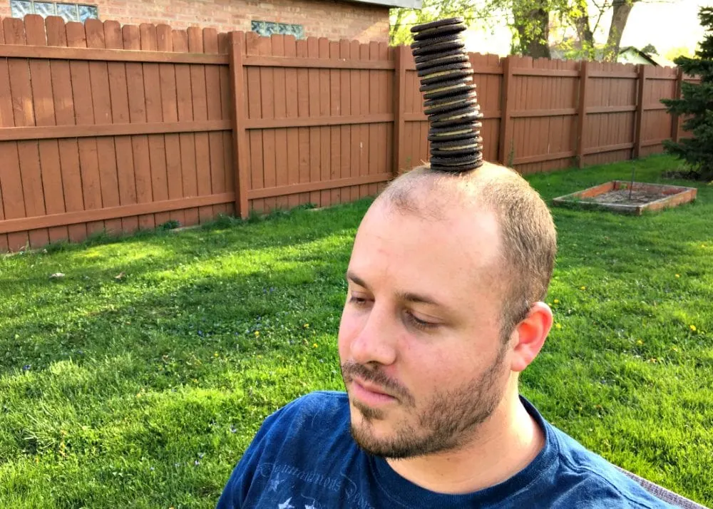 Man with a stack of oreo cookies on his head. 