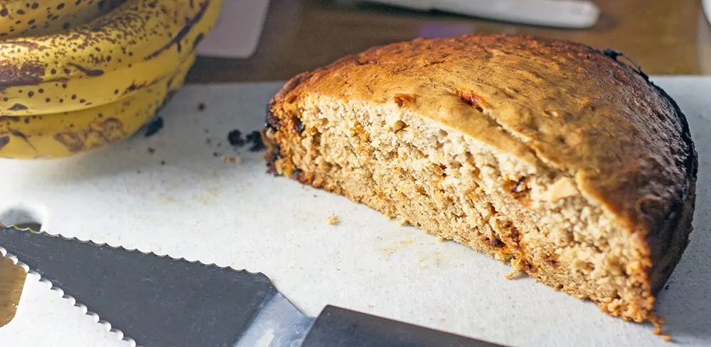 Ripe bananas and a loaf of banana bread on a cutting board. 