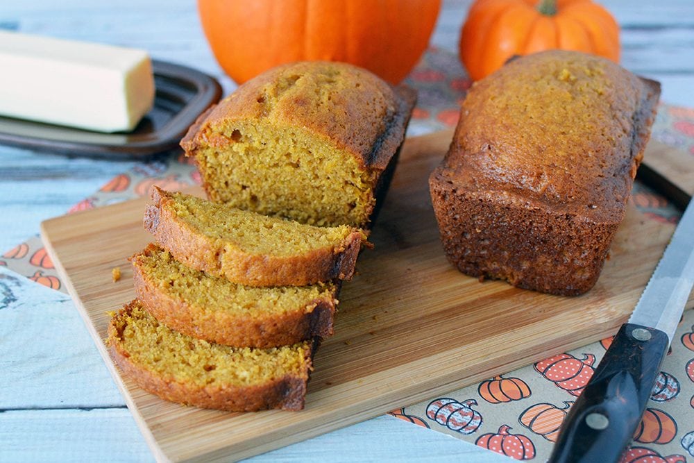 Pumpkin bread sliced on a board next to butter.