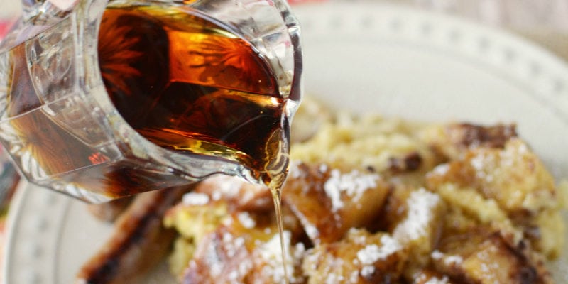 Pouring syrup on a plate of french toast. 