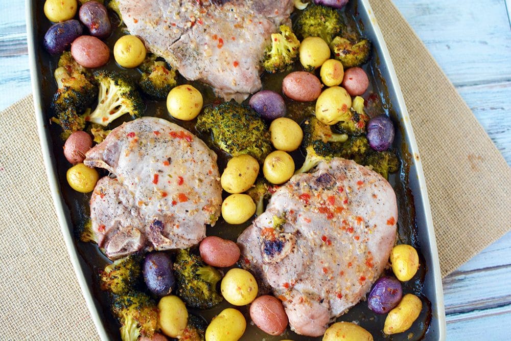 Pork chops with potatoes and broccoli on a sheet pan.