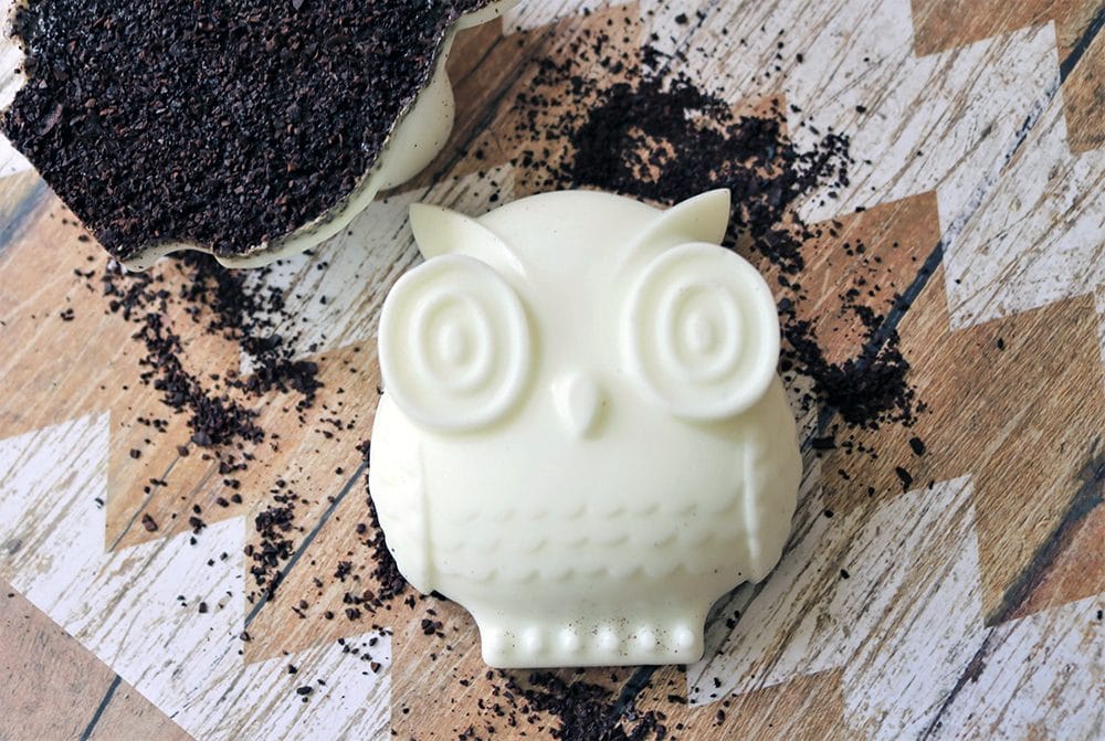 Owl-shaped soap on a table with coffee grounds. 
