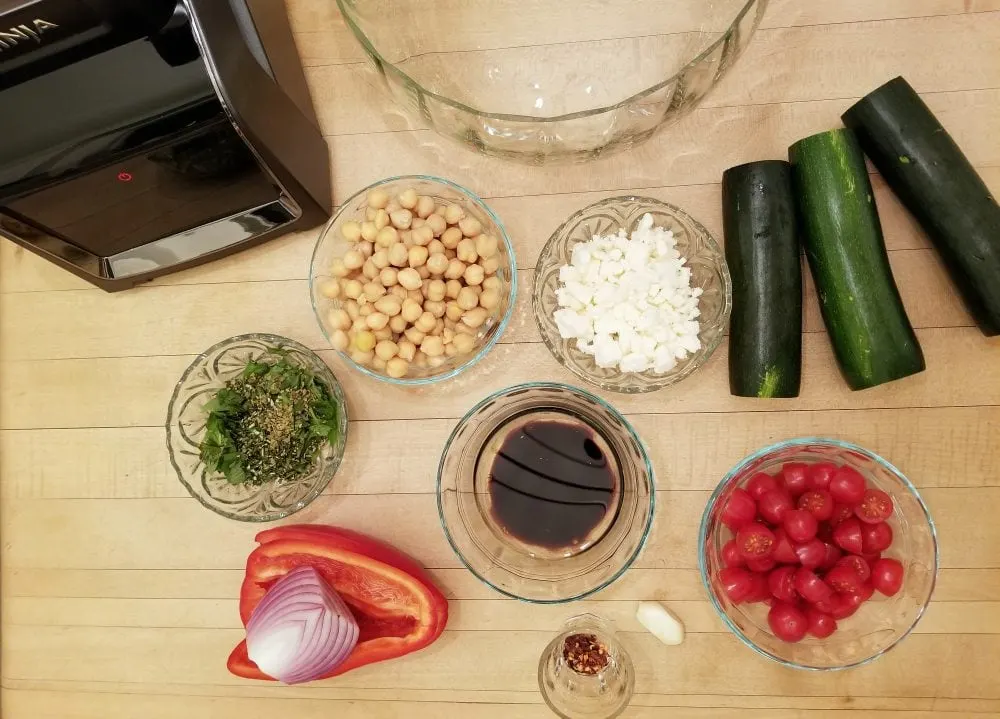Chickpeas, tomato, pepper, and other ingredients in bowls. 