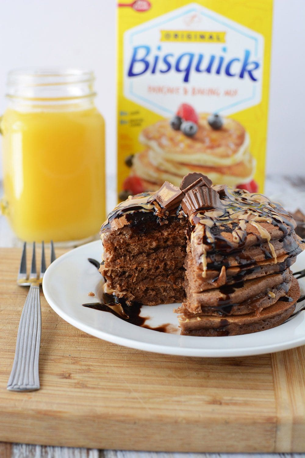 Chocolate PB pancakes on a plate in front of orange juice and a box of Bisquick. 