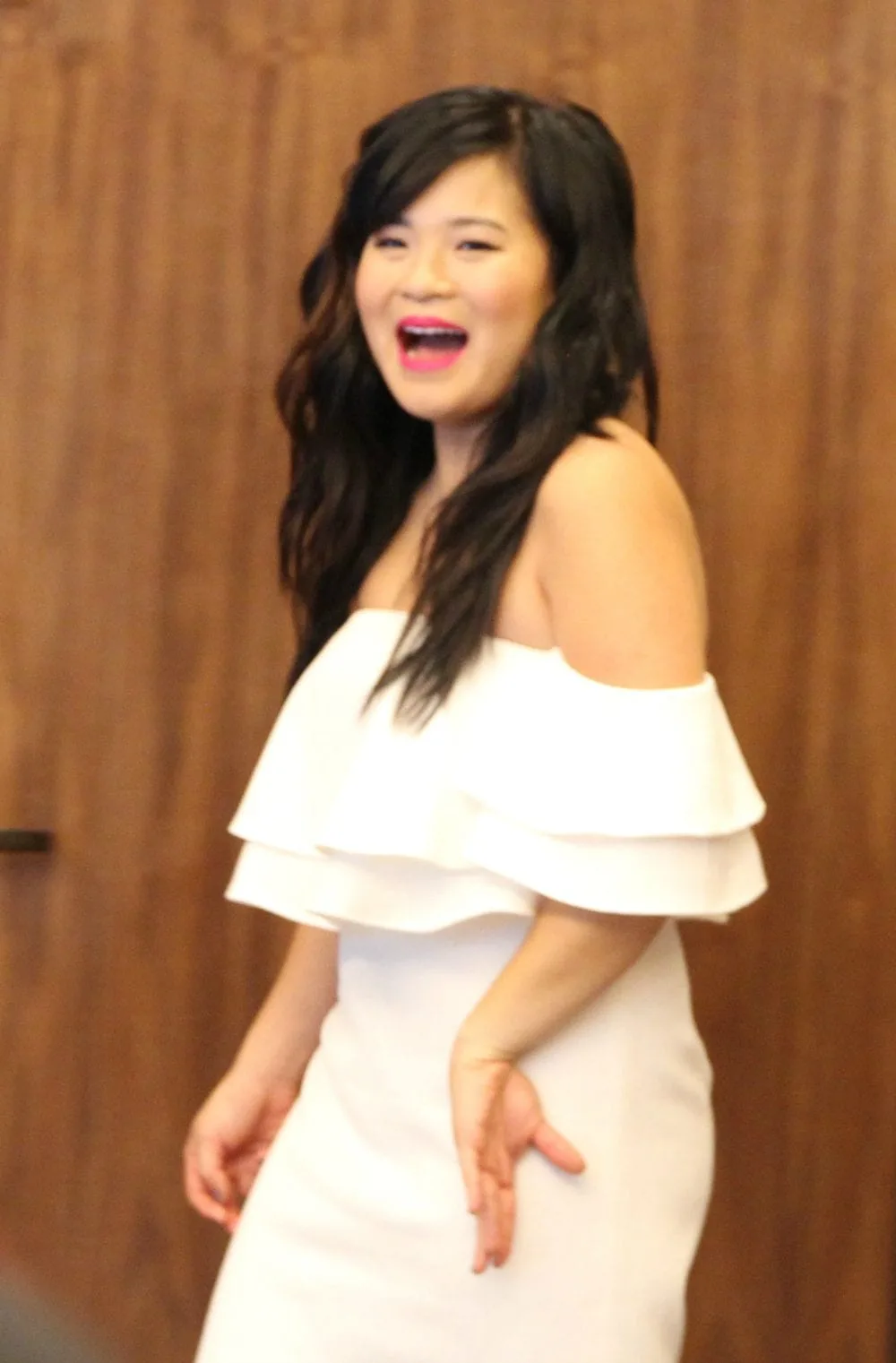 Kelly Marie Tran smiling in a white dress. 