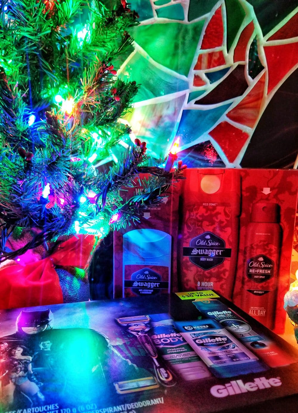 Gift sets of Old Spice and Gillette next to a Christmas tree with a stained-glass background. 